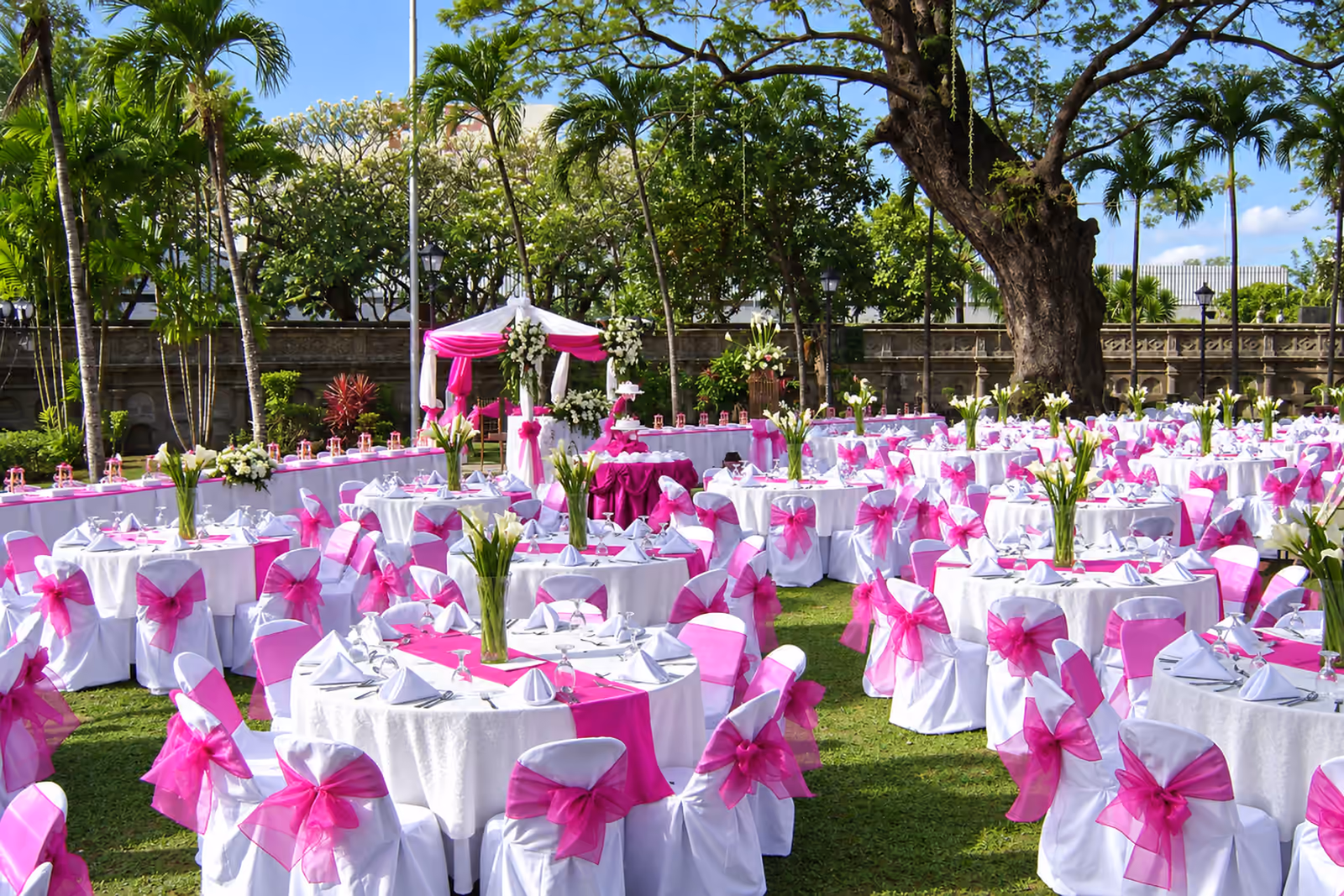 Jojie's outdoor catered event with white-dressed tables and magenta accents